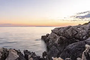 Eastern European Landscape Drucke: Gentle ocean waves eroding ancient rocks under a tranquil evening sky