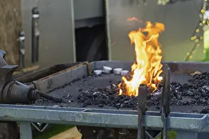 Traditional European Crafts Drucke: A glowing forge fire on a coal bed with burning flames in a workshop environment