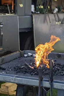 Traditional German Craftsmanship Drucke: A glowing forge fire on a coal bed with burning flames in a workshop environment