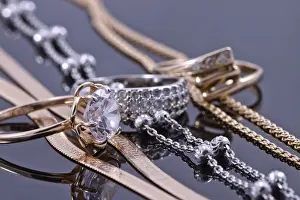Precious Stones Drucke: Gold ring, earrings and chains on a reflective surface