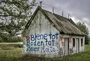Wandmalereien Drucke: Graffitis auf dem verfallenen Strohdachhaus.