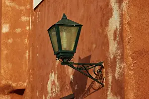Monemvasia Greece Drucke: A green lantern hangs on a rust-tinted wall with distinct texture