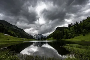 Central Europe Countryside Photo Drucke: Groppelensee with reflection of the Altmann summit in the background under a threatening cloudy sky