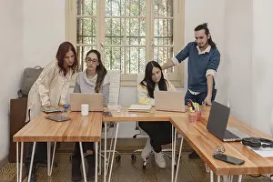 Colleagues Working Together Drucke: A group of four colleagues collaborating in an office