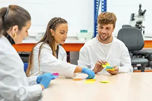 Young Scientists In Lab Drucke: Group of scientists sitting in a table of a laboratory during a brainstorming process
