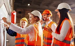 Workplace Communication Strategies Drucke: The group of workers stands next by the flip chat and plans work