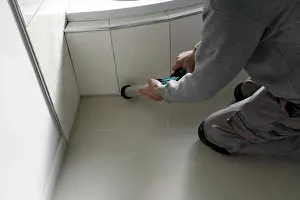 Ceramic Tile Installation Drucke: Grouting work. Tiler grouting in a new bathroom