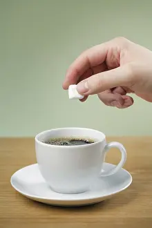Hot Beverage Drink Drucke: A Hand adding sugar to a cup of black coffee