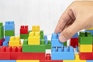 No People On Site Drucke: Hand building up a wall by stacking up block