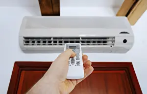Hand Holding Remote Control Drucke: Hand holding remote control in front of the air conditioner