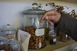 Hippokrates Drucke: Eine Hand reicht in ein Glas voller Eicheln auf einem Regal.