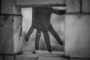 Deserted Wedding Scene Drucke: Hand with wedding ring being seen from a whole in a brick wall