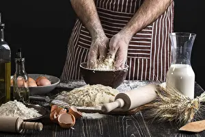 Kitchen Utensils Drucke: A handful of flour with egg on a rustic kitchen