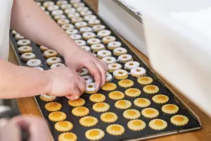 European Desserts Drucke: Two hands decorating double-layered round biscuits on a baking tray