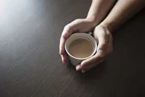 Coffee Break Drucke: Hands hold a hot cup of coffee on a table