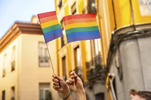 LGBTQ Pride Drucke: Hands are raising two small rainbow flags