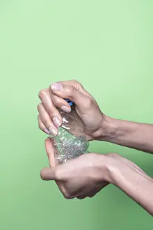 Plastic Recycling Drucke: Two hands squeeze a clear plastic bottle