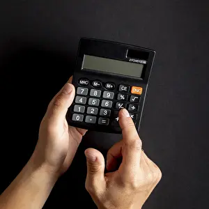 Capital Market Symbolism Drucke: Hands using black mini calculator