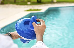 Swimming Pool Disinfection Drucke: Hands of a worker installing a pool chlorine float