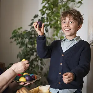 Easter Traditions And Customs Drucke: Happy boy holding a broken painted Easter egg
