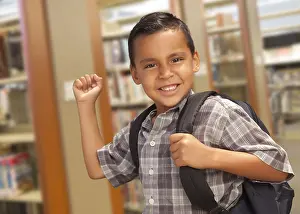 Hispanic Child Learning Drucke: Happy hispanic student boy with backpack in the library