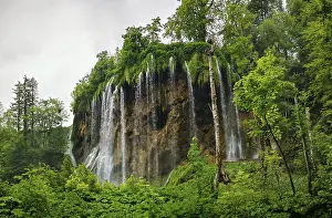 Nature Reserve Europe Drucke: High waterfall flows over a rock wall surrounded by thick