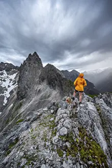 German Alps Landscape Photography Drucke: Hiker looking at mountains under dramatic clouds