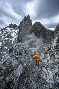 Hiker In The Alps Drucke: Hiker looking at mountains under dramatic clouds