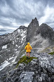 Hiker In The Alps Drucke: Hiker looking at mountains under dramatic clouds