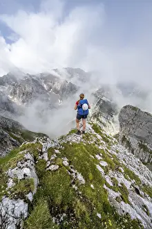 German Alps Landscape Photography Drucke: Hiker looking at mountains under dramatic clouds