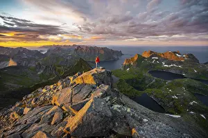 Hiker At Summit Drucke: Hiker stands at the summit, sunset with dramatic clouds