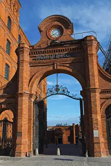Brick Building Entrance Drucke: A historic brick gate with a clock