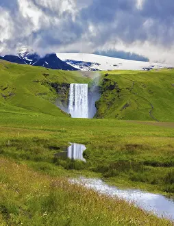 Iceland Waterfalls Drucke: The huge deep falls Skogafoss are reflected in small stream