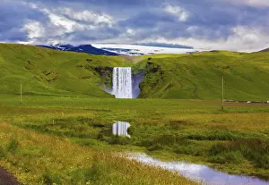 European Waterfalls Drucke: The huge deep falls Skogafoss are reflected in small stream