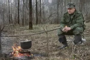 Campfire Cooking Drucke: The hunter makes a dinner on a bonfire
