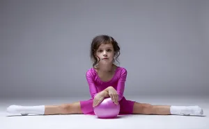 Studio Shot Girl Drucke: Image of adorable little gymnast posing on split in studio