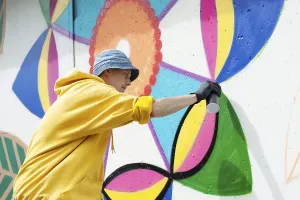 Straßenkünstler Drucke: Bild eines konzentrierten jungen Mannes, der auf einer Wand Graffiti malt.