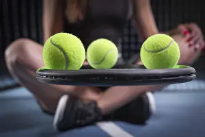 Athletic Young Female Drucke: Image of a set of tennis balls lying on the strings of a racket