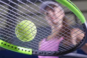 Young Woman Playing Tennis Drucke: Image of a tennis ball on the background of the strings of the racket