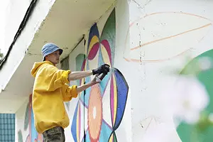Straßenkünstler Drucke: Bild eines jungen Mannes, der auf Wand mit Sprühdose malt.