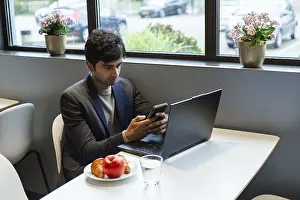 Remote Work Lifestyle Drucke: A indian man multitasks efficiently using a smartphone