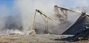 Raw Material Extraction Site Drucke: Industrial background, crusher rock stone crushing machine at open pit mining and processing plant for crushed stone