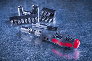 Construction Equipment Drucke: Insulated screwdriver with replaceable bits and heads on scratched metallic background construction concept