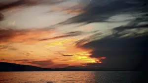 Atmospheric Light Of The Setting Sun Drucke: Intense sunset with dramatic cloud formations over water