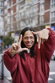 Joyful Facial Expression Drucke: A joyful man in a red jacket creates a frame with their hands