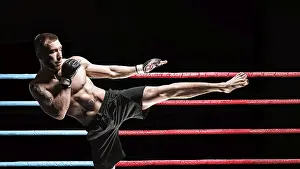 Fitness Model Male Drucke: Kickboxer posing in the ring. Middle Kick