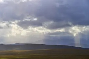 Northern Europe Nature Scenery Drucke: Landscape with rolling hills and rays of light breaking through dramatic clouds