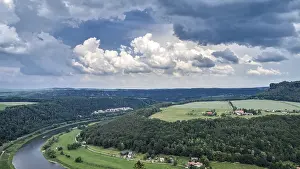 German Landscape Photography Drucke: Landscape with a winding river and vast fields under a dramatic sky