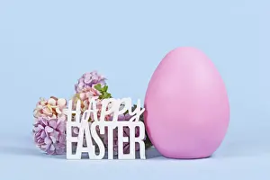 Colorful Still Life Drucke: Large pink Easter egg, hydrangea flowers and text Happy Easter on blue background