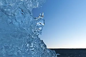 Evening Light On Water Drucke: Light reflections in a stranded piece of iceberg after sunset